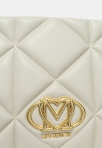 Borsa a tracolla in finta pelle crema trapuntata con hardware dorato inciso con "LOVE MOSCHINO" nella parte inferiore.