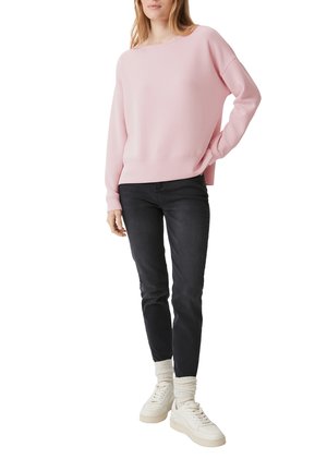 Felpa oversize rosa chiaro con orlo a coste, abbinata a jeans scuri e sneaker bianche, caratterizzata da una vestibilità comoda e una texture morbida.