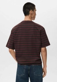 Burgundy and black striped short-sleeve t-shirt with a relaxed fit and a round neck, shown from the back, paired with denim jeans.