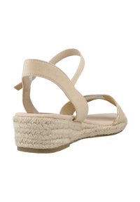 Beige espadrille sandaal met een sleehak. Voorzien van canvas banden en een gevlochten jute zool. Ontwerp met open achterkant en enkelriem.