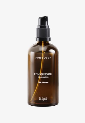 Amber pump bottle of Jungluck cleansing oil with mild formula containing organic argan and jojoba oils on a white background.