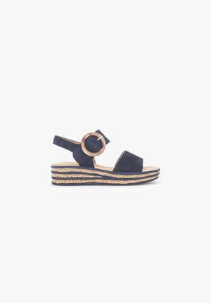 Sandale compensée bleu marine avec bride de cheville ajustable, détail de boucle circulaire et semelle intermédiaire en jute tissé avec un design superposé.