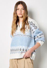 Sweter robiony na drutach w niebiesko-białej kolorystyce, z geometrycznym wzorem, kołnierzykiem oraz ściągaczami na mankietach i dolnej krawędzi.