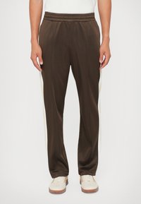 Bruine sportbroek met witte zijkanten, gemaakt van gladde stof, met een elastische tailleband en een recht model.