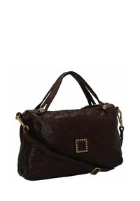 Bruine leren handtas met gestructureerde afwerking, dubbele handvatten, lange schouderriem en gouden studs aan de voorkant. Ritsafsluiting en decoratieve hardware.