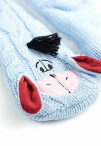 Mittens blu fatto a maglia con un motivo a trecce, con il volto di Eeyore, orecchie pelose grigie e rosse, e una ciuffo di filato nero sopra.