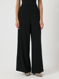 Μαύρο παντελόνι με φαρδιά μπατζάκια από μαλακό ύφασμα, με ψηλή μέση και πλισέ μπροστά. Η λεία υφή και οι καθαρές γραμμές τονίζουν το σχέδιο.