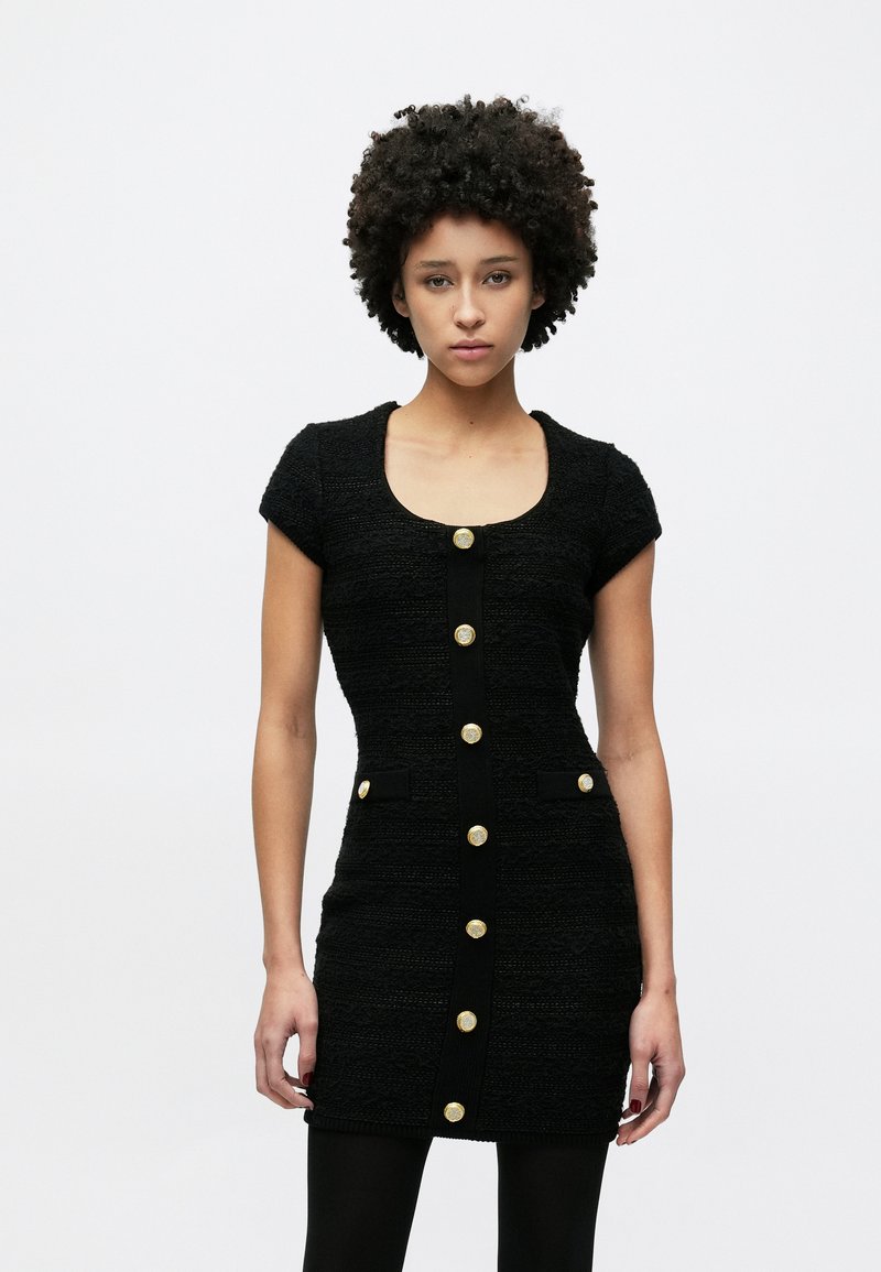 Μαύρο structured φόρεμα με κοντά μανίκια, υφή υφάσματος, μεγάλα χρυσά κουμπιά κατά μήκος του μπροστινού μέρους και δύο μικρές τσέπες στη μέση.