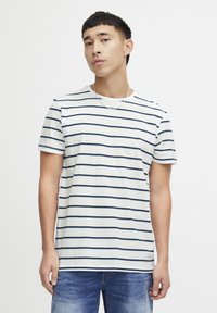 Stripet bomulls t-skjorte med marineblå striper på hvit bakgrunn, med korte ermer og rund hals. Bæres med dongeri jeans.