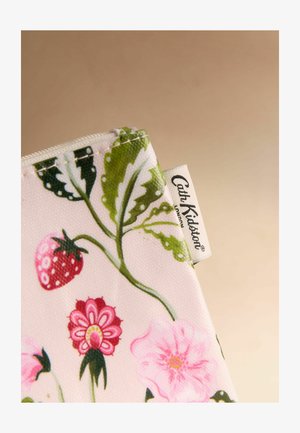 Lähikuva kankaasta, jossa vihreitä lehtiä, punainen mansikka, vaaleanpunaisia kukkia ja valkoinen etiketti, jossa lukee Cath Kidston.