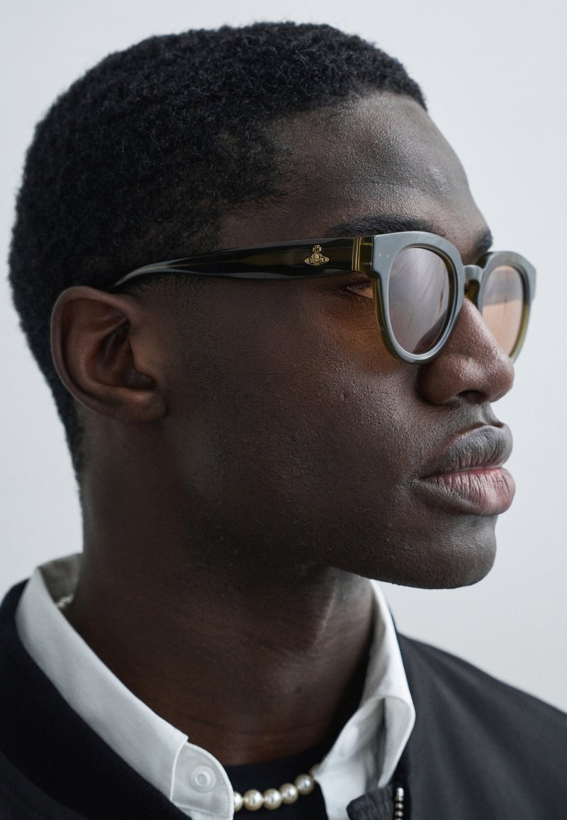 Tortoiseshell sunglasses with brown tinted lenses, featuring a gold emblem on the temple. The frames have a rectangular shape and glossy finish.