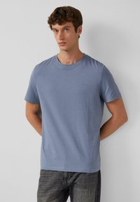 Lichtblauwe katoenen t-shirt met korte mouwen en een ronde hals. Bevat een klein logo op de borst en heeft een ontspannen pasvorm. Effen structuur.
