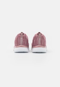 Różowe tekstylne sneakersy z plecionym wzorem, z uchwytami z tyłu i białymi gumowymi podeszwami, posiadające delikatną teksturę i wzory.