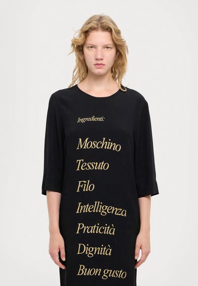 Black dress featuring gold embroidered text, including the word "Ingredienti:" and various descriptors. Soft fabric, loose fit, three-quarter sleeves.