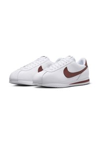 White athletic shoes with a smooth leather finish, featuring a maroon swoosh design, flat laces, and a rubber sole with zigzag tread.