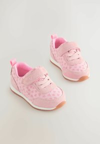 Baskets roses avec une tige en daim doux, un tissu à motifs de cœurs, des lacets élastiques et des bandes Velcro ; semelle blanche avec des accents en caoutchouc brun.