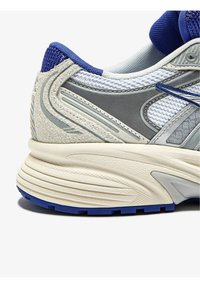 Scarpa da corsa da uomo con tomaia in mesh bianco, accenti grigi, dettagli tessili blu e una suola spessa color crema con motivo di trazione blu.