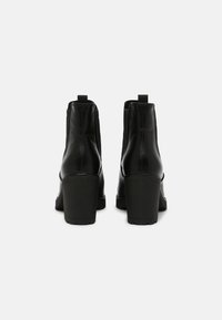 Black leather ankle boots with a smooth texture, elastic side panels, and chunky heels. Features a loop for easy wear.