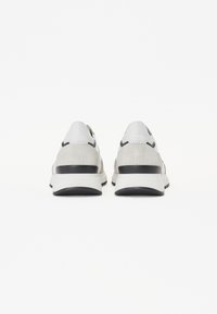 Szare i czarne sneakersy wykonane z połączenia gładkich i teksturowanych materiałów, z grubą podeszwą i kontrastowymi akcentami wzdłuż pięty.