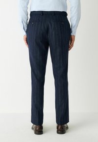 Haditengerészeti csíkos nadrág, texturált anyagból készült, két hátsó zsebbel, gombos záródással, testhezálló fazonnal és egyenes lábakkal.