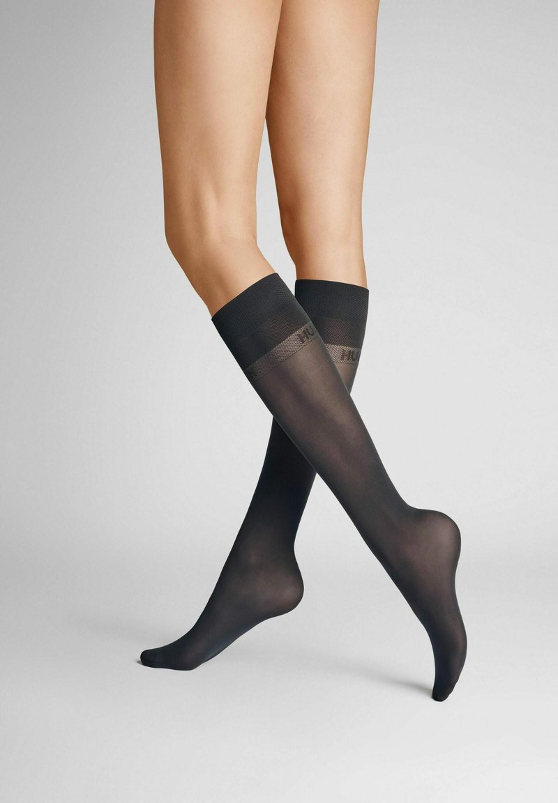 Knielange schwarze Socken aus durchsichtigem Material, mit einem soliden Band oben und Logodetails sowie einer glatten Textur.