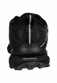 Zapato deportivo negro con un acabado texturizado, talón reforzado, acentos reflectantes y logo en la suela, diseñado para el rendimiento y la estabilidad.