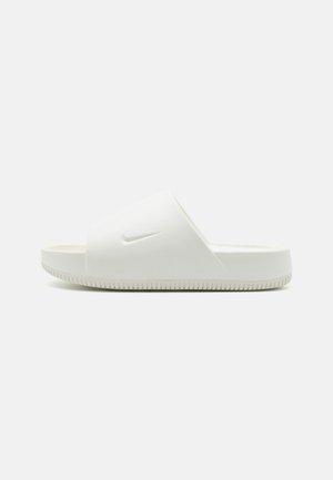 Hvid Nike slidesandal med tyk sål og bred rem over foden med et diskret præget Nike swoosh-logo.