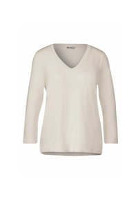Top a maniche lunghe beige chiaro con scollo a V realizzato in tessuto morbido, caratterizzato da una vestibilità rilassata e un design semplice senza motivi o decorazioni visibili.
