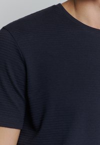 Donkerblauwe, nauwsluitende T-shirt met een gestructureerd ribbelpatroon, ronde halslijn en korte mouwen.