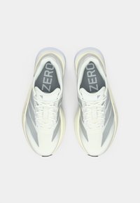 Ελαφριά παπούτσια τρεξίματος σε λευκό και γκρι με αναπνεύσιμο πάνω μέρος από δίχτυ, στρογγυλεμένη μύτη και παχιά σόλα από καουτσούκ. Φέρουν το λογότυπο "ZERO".