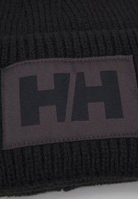 Beanie nera lavorata a maglia con un motivo testurizzato. Presenta un'etichetta rettangolare nera con il logo "HH" in evidenza, di colore nero opaco.