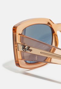 Óculos de sol Ray-Ban com armações grandes e translúcidas na cor laranja e lentes azul-escuras. Apresenta um logótipo dourado e elegantes detalhes laterais.