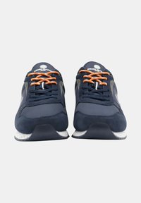 Marinblå sportskor med mocka- och meshmaterial, prydda med orange snören, grå detaljer och en vitprickig sula.