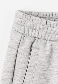 Harmaat verkkarit, joissa on joustava vyötärö, pehmeä kangas ja sivutaskut virtaviivaisilla ompeluyksityiskohdilla.