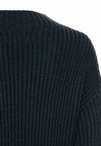 Dunkelblauer gerippter Strickpullover mit hohem Halsausschnitt, der horizontale und vertikale Muster für zusätzlichen Detailreichtum aufweist.