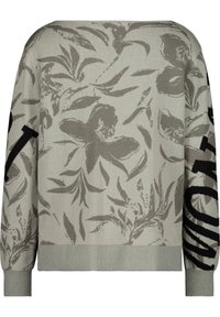 Pull gris clair avec un motif floral en gris foncé et des lettres noires sur une manche. Poignets et ourlet côtelés. Texture douce.