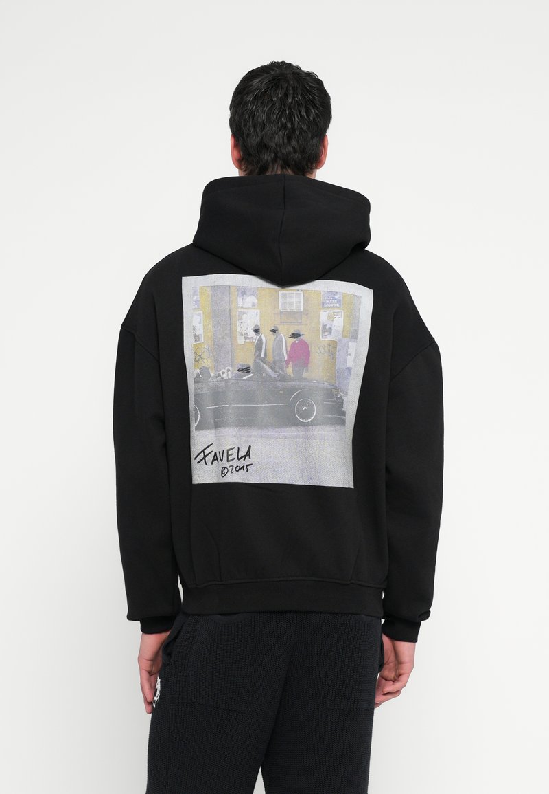 Fekete kapucnis pulóver nagy fényképes mintával a hátoldalán, utcai jelenettel és alakokkal. Puha anyag, kényelmes szabás, kenguruzseb.