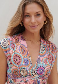 Robe à motifs floraux avec des couleurs vives comme le rose, l'orange et le bleu, dotée d'un décolleté en V et de manches courtes ; texture de tissu lisse.