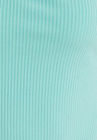 Gros plan d’un tissu côtelé turquoise clair avec une texture tricotée verticale montrant des courbes subtiles.