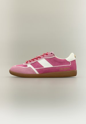 Pantof sport roz și alb, cu șireturi roșii, talpă maro și logo auriu „Steve Madden” pe lateral, pe un fundal simplu.