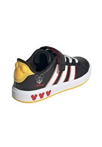 Scarpe sintetiche nere con strisce rosse e bianche, cinturino in velcro e tacco giallo con dettagli di Topolino e logo. Suola bianca con dettagli rossi.