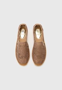 Lace espadrilles in lichtbruin met een geweven jute zool, versierd met bloemmotieven en een glanzende, metalen binnenzool. Instapmodel.