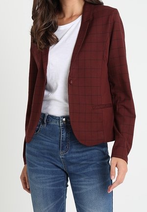 Bordeaux geruite blazer met een reverskraag, enkele knoopsluiting en twee voorzakken, gecombineerd met een wit t-shirt en blauwe jeans.