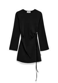 Svart långärmad klänning i mjukt tyg, med en draperad sidoknut och rund halsringning, rak fåll och minimalt med detaljer.
