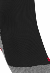 Czarna skarpetka o teksturowanej powierzchni, szarym pięcie i czerwonym logo. Projekt charakteryzuje się oddychającym wzorem splotu i kontrastującymi kolorami.