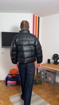 Black padded puffer jacket with a glossy finish, featuring embossed lettering on the shoulders and a classic collar design.