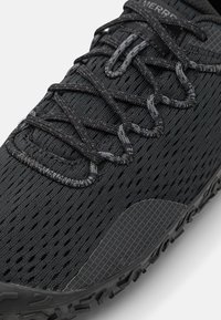 Black athletic shoe featuring a breathable mesh upper with textured pattern, reinforced toe cap, and rubber outsole with traction.
