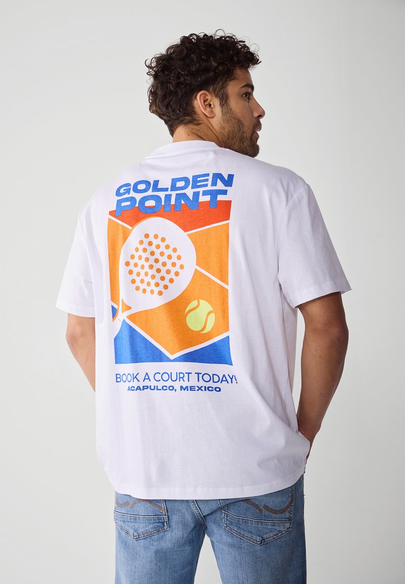 Hvit bomullstrøye med et fargerikt grafisk design på ryggen, som inkluderer tekst, en paddle og en tennisball i blått, oransje og gult.