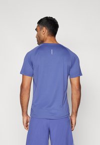 Camisola atlética roxa com mangas curtas e decote redondo. Apresenta um detalhe sutil do logótipo nas costas e um tecido liso e elástico.