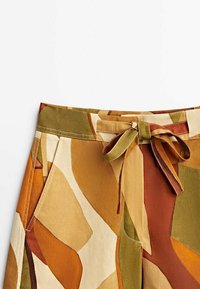 Multicolored trousers featuring a pattern of earthy tones in orange, brown, and green. Includes a tied waist and side pockets.